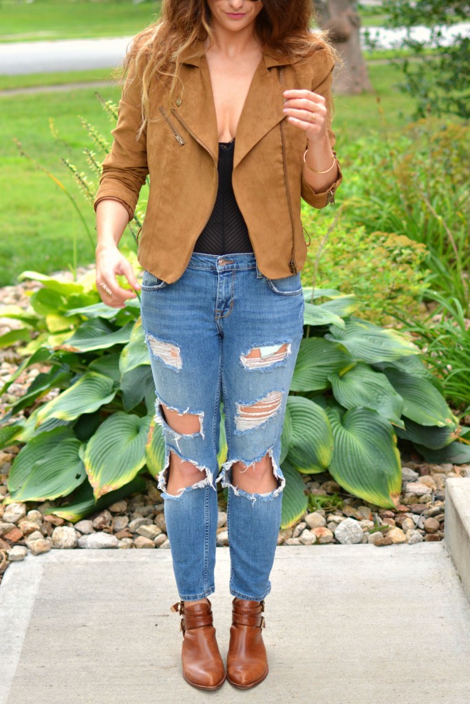 ashley from lsr in a faux suede jacket, ripped jeans, sheer bodysuit, and ankle booties