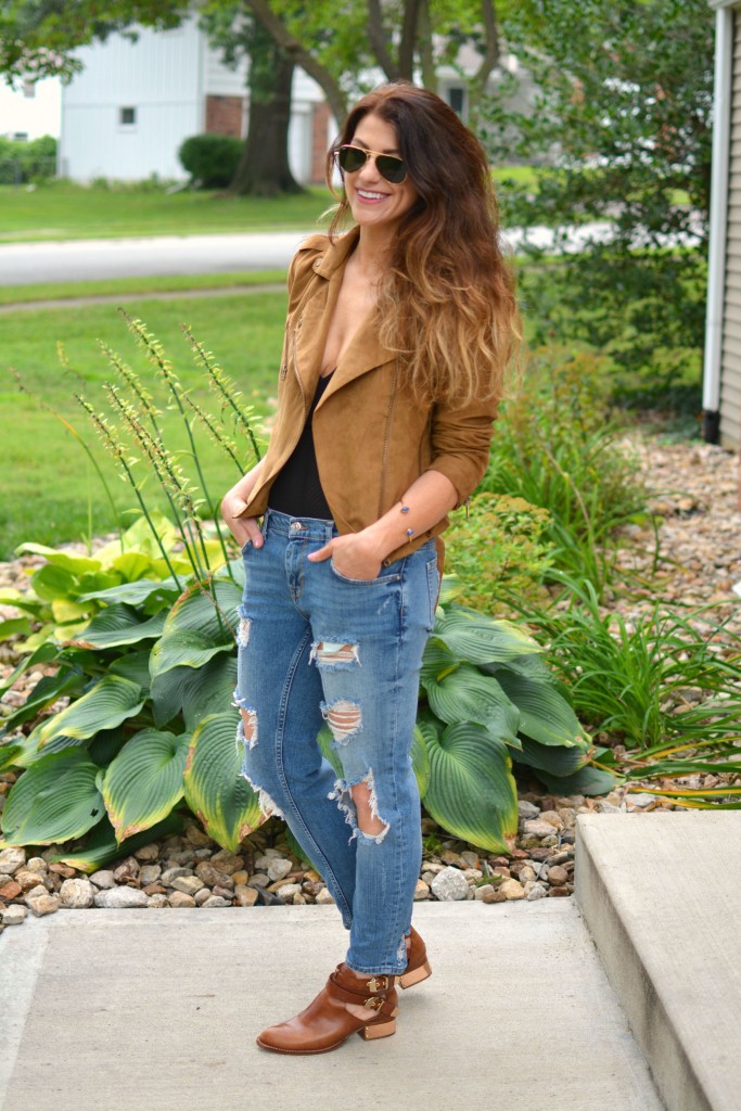 ashley from lsr in a faux suede jacket, ripped jeans, sheer bodysuit, and ankle booties