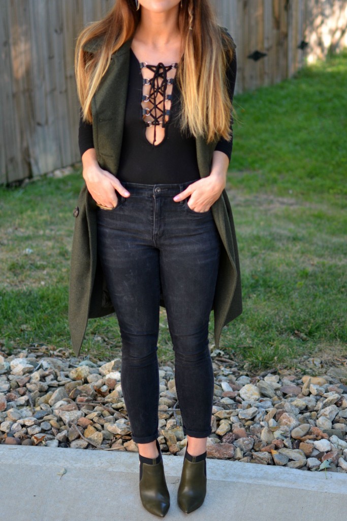 Ashley from LSR in a sleeveless military peacoat, a lace-up bodysuit, black Madewell jeans, and olive stiletto booties