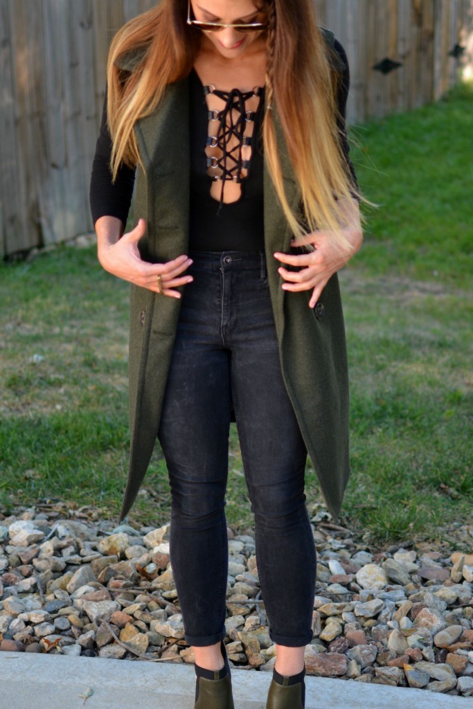 Ashley from LSR in a sleeveless military peacoat, a lace-up bodysuit, black Madewell jeans, and olive stiletto booties