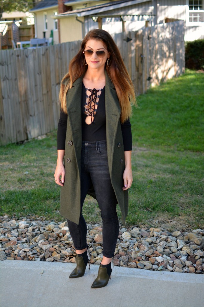 Ashley from LSR in a sleeveless military peacoat, a lace-up bodysuit, black Madewell jeans, and olive stiletto booties