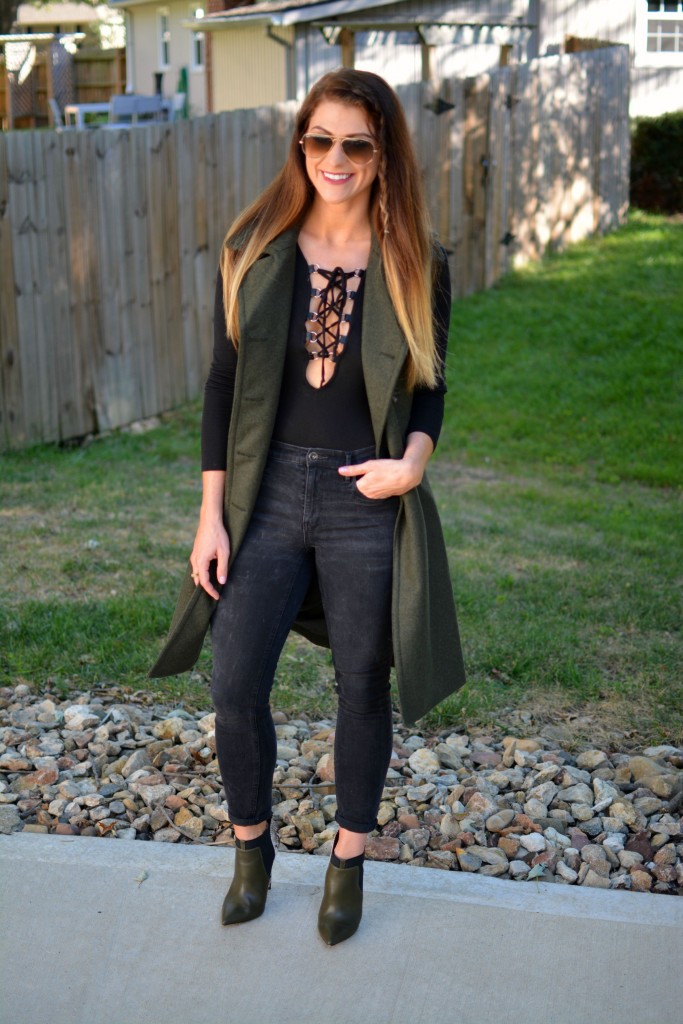 Ashley from LSR in a sleeveless military peacoat, a lace-up bodysuit, black Madewell jeans, and olive stiletto booties