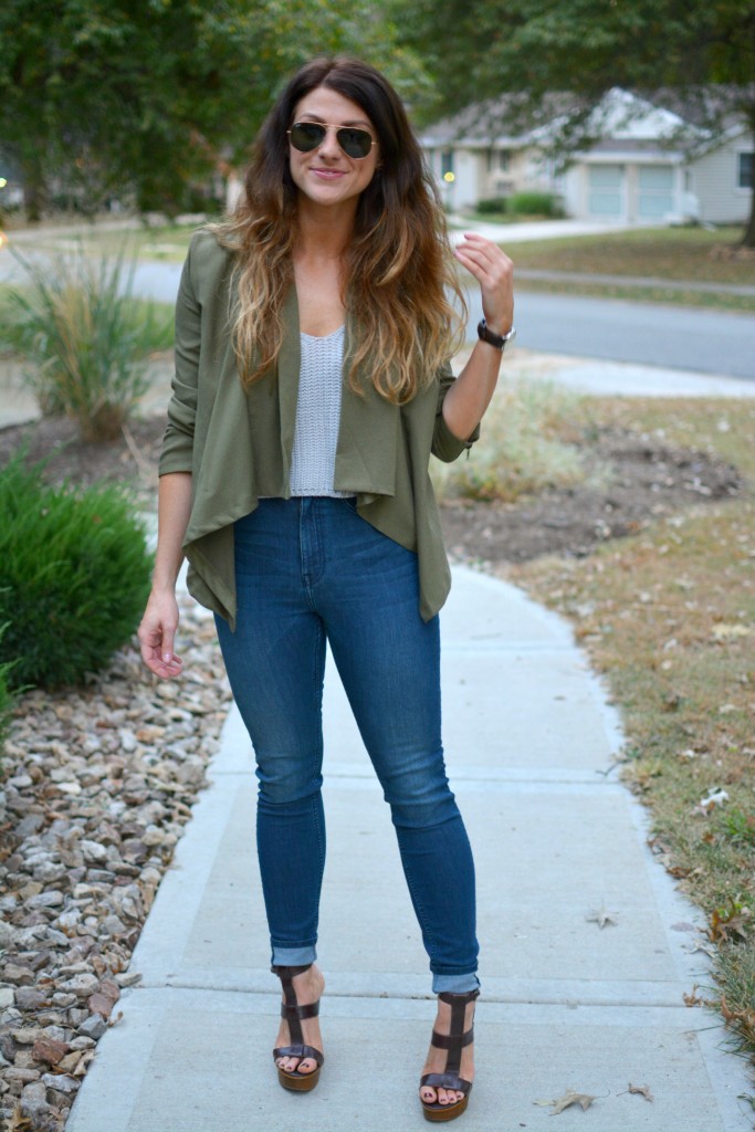 Ashley from LSR in an olive green jacket and gray crochet SheIn crop top, with high-waisted skinny jeans and gladiator sandals.