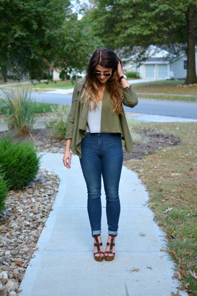 Ashley from LSR in an olive green jacket and gray crochet SheIn crop top, with high-waisted skinny jeans and gladiator sandals.