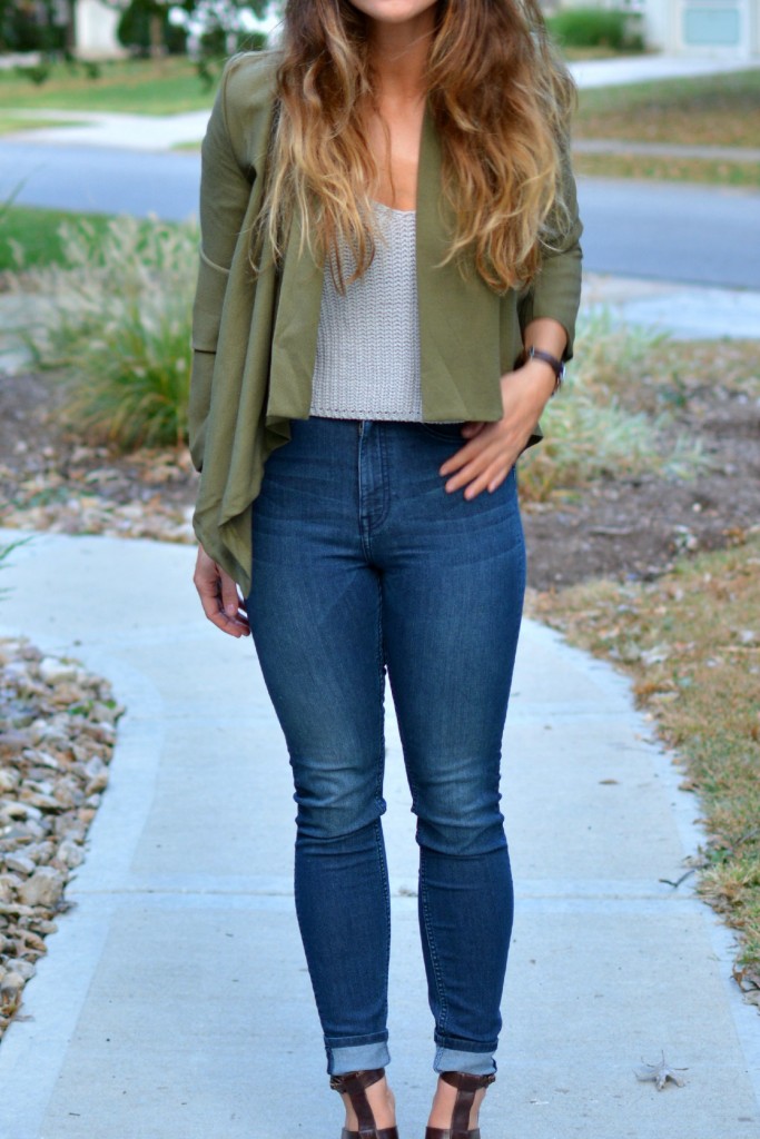 Ashley from LSR in an olive green jacket and gray crochet SheIn crop top, with high-waisted skinny jeans and gladiator sandals.