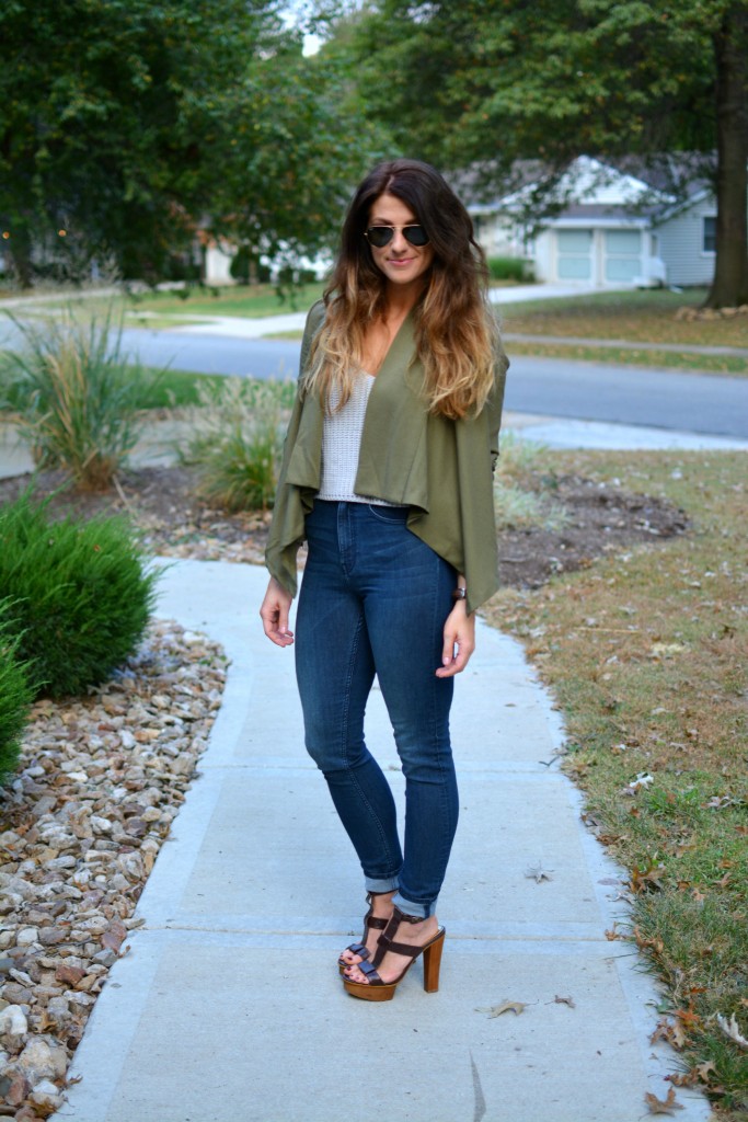 Ashley from LSR in an olive green jacket and gray crochet SheIn crop top, with high-waisted skinny jeans and gladiator sandals.