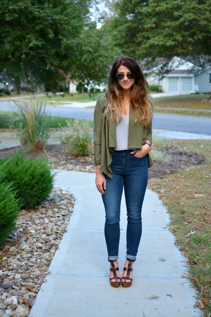 Ashley from LSR in an olive green jacket and gray crochet SheIn crop top, with high-waisted skinny jeans and gladiator sandals.