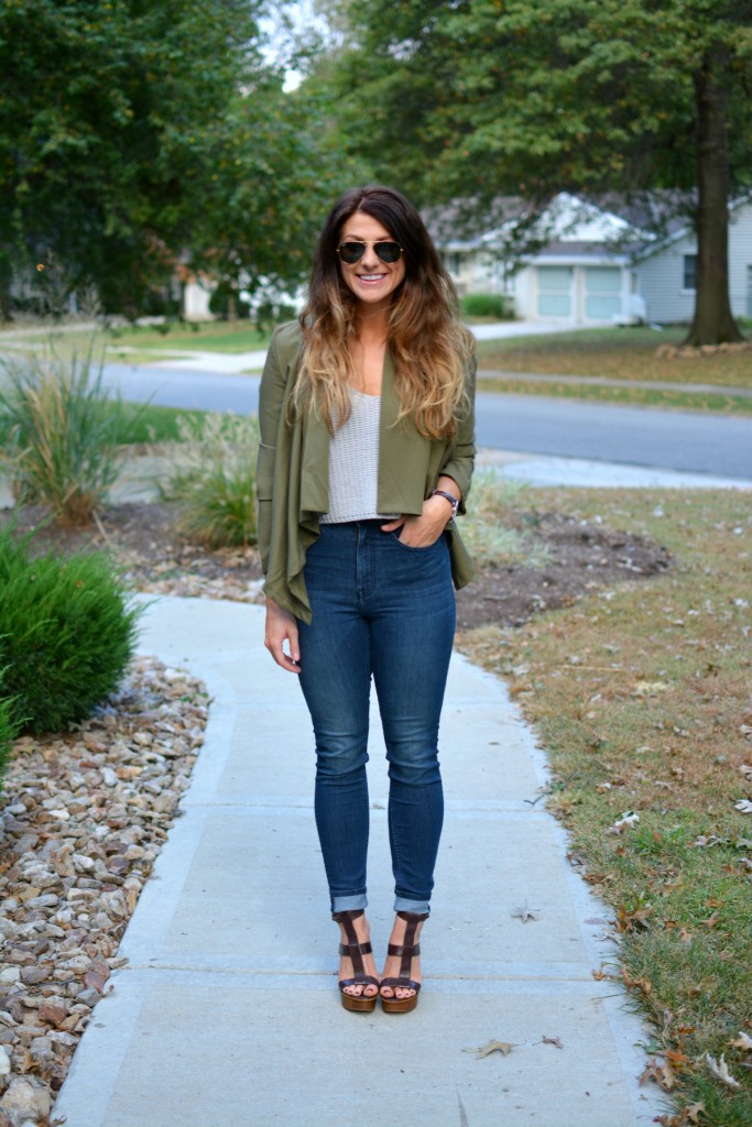 Ashley from LSR in an olive green jacket and gray crochet SheIn crop top, with high-waisted skinny jeans and gladiator sandals.