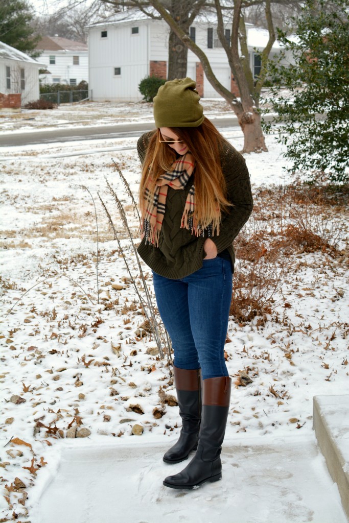 Ashley from LSR in an olive sweater, two-tone riding boots, a beanie, and a Burberry scarf