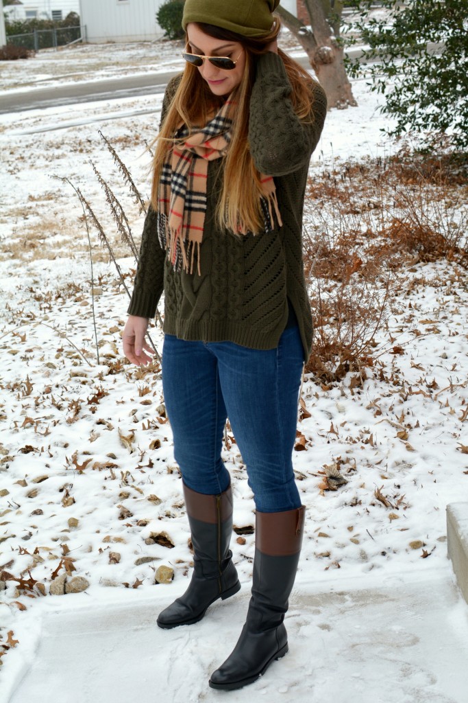 Ashley from LSR in an olive sweater, two-tone riding boots, a beanie, and a Burberry scarf