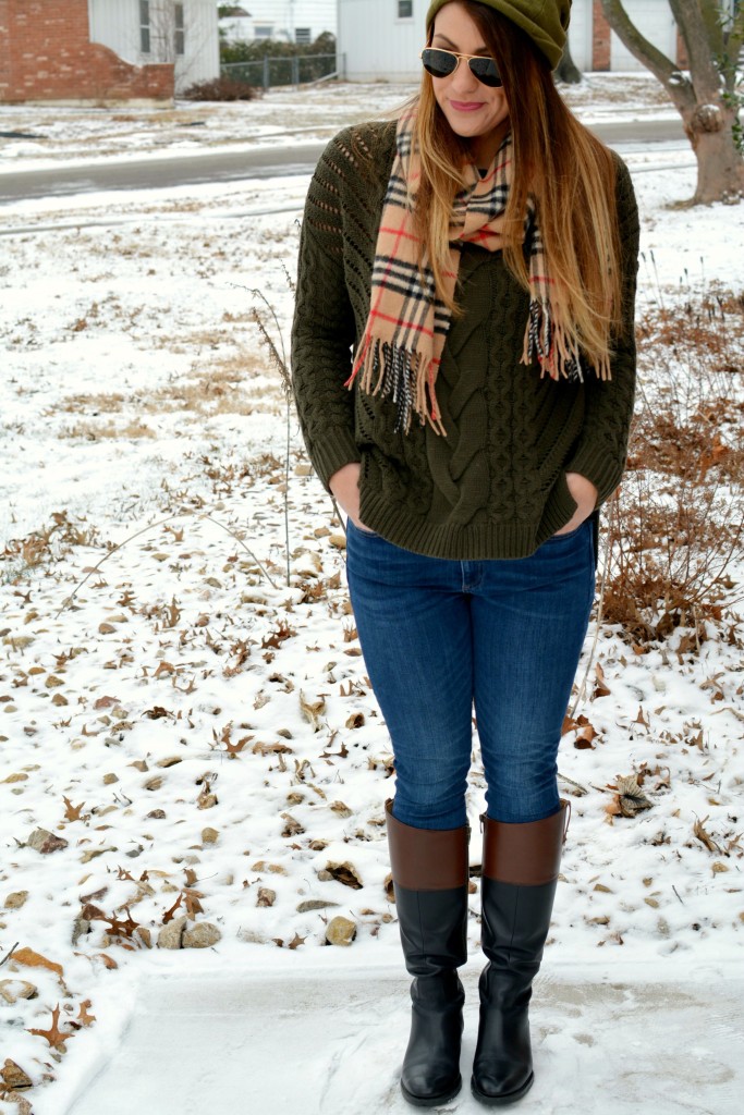 Ashley from LSR in an olive sweater, two-tone riding boots, a beanie, and a Burberry scarf