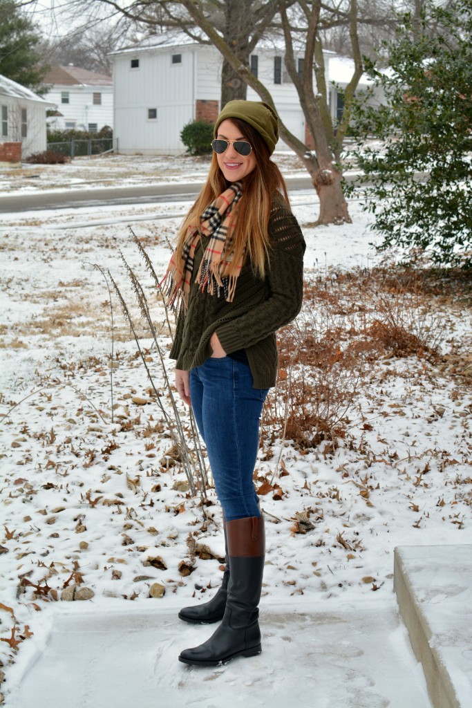 Ashley from LSR in an olive sweater, two-tone riding boots, a beanie, and a Burberry scarf