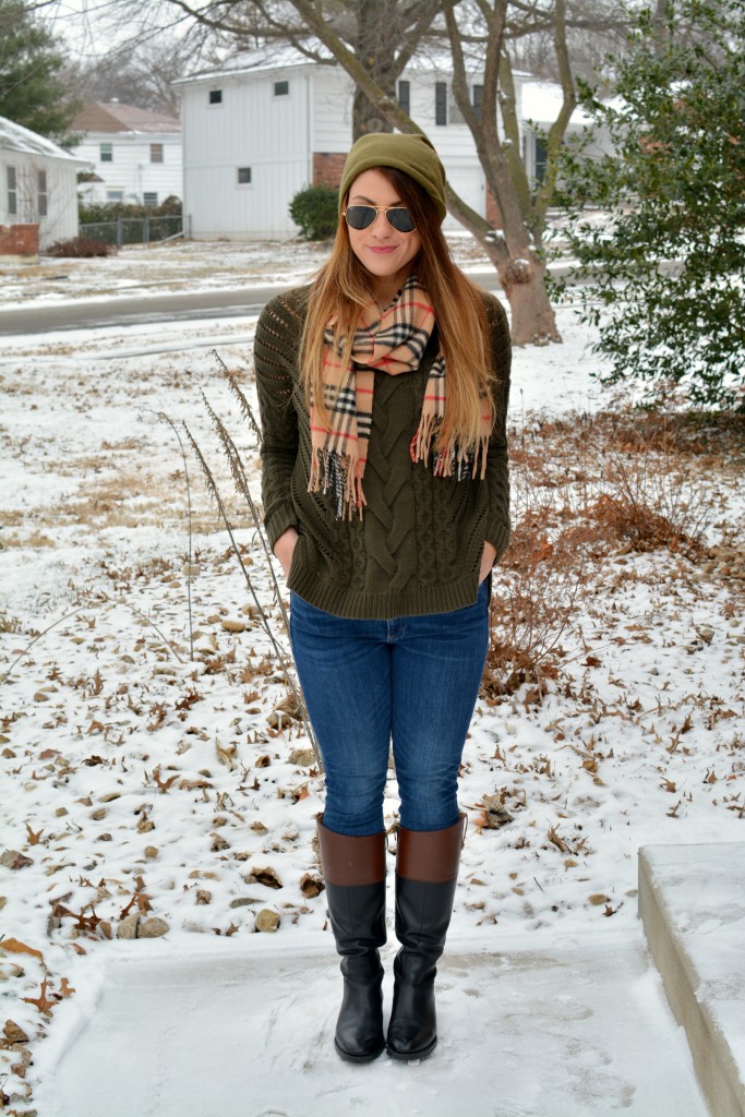 Ashley from LSR in an olive sweater, two-tone riding boots, a beanie, and a Burberry scarf