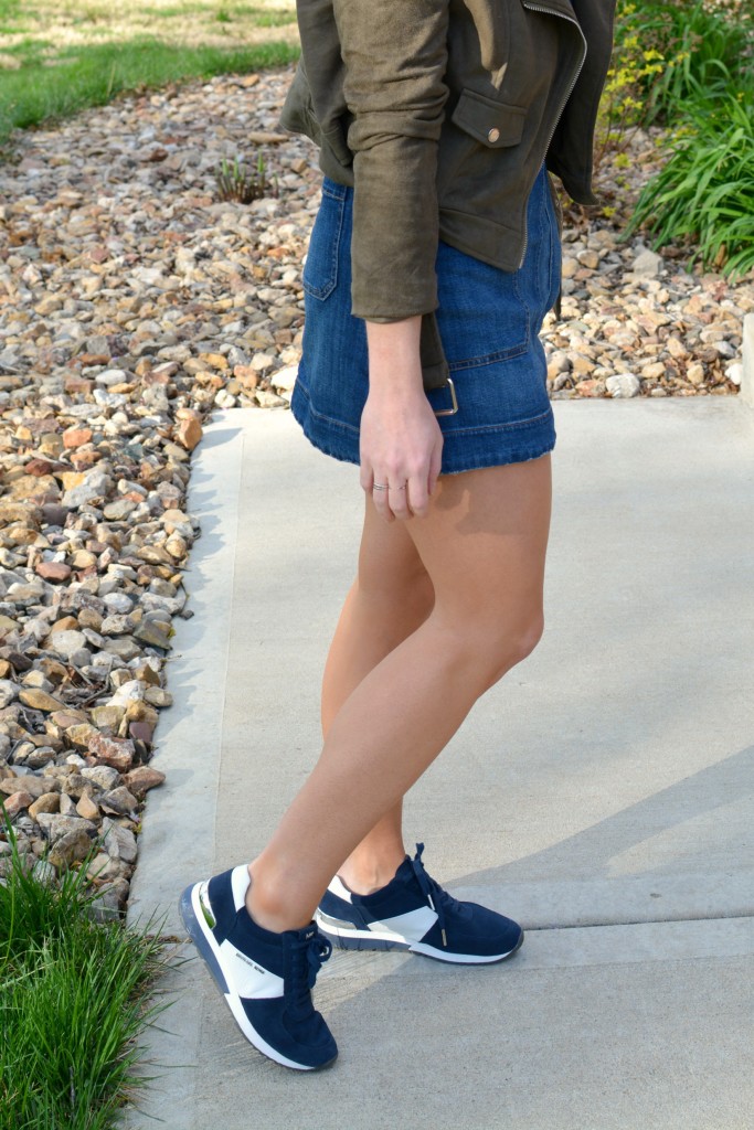 Ashley from LSR in an overall dress, suede jacket, and retro sneakers