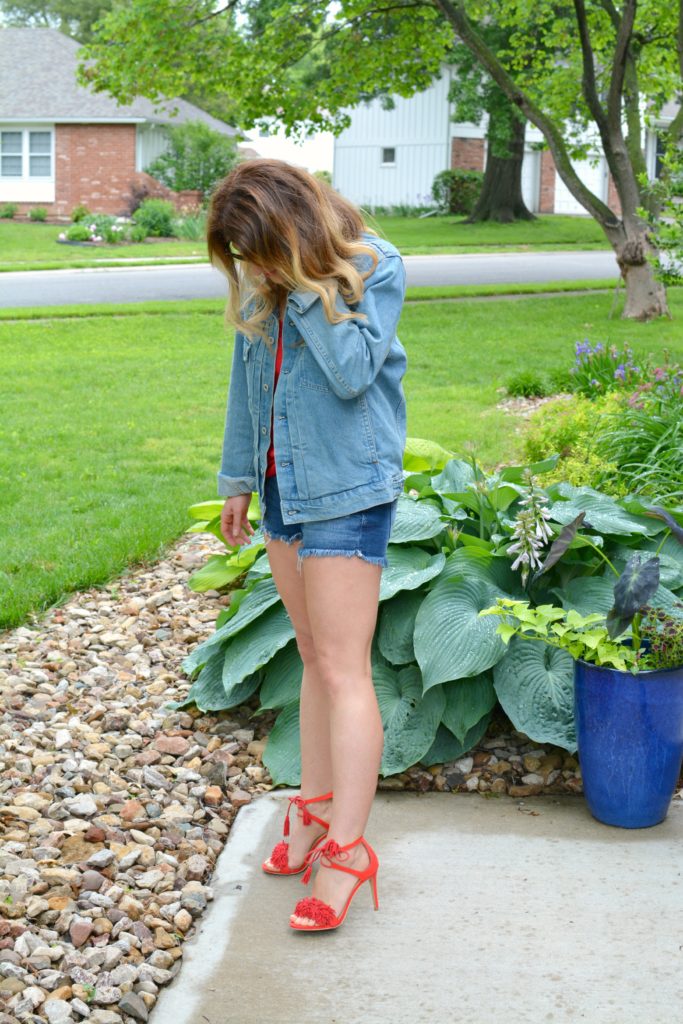 Ashley from LSR in a men's denim jacket, cutoff shorts, and red fringe sandals