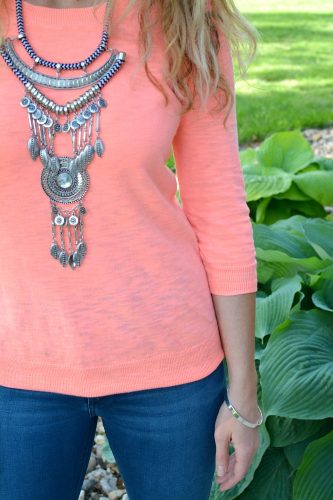 Ashley from LSR in a neon coral sweater and a silver statement necklace