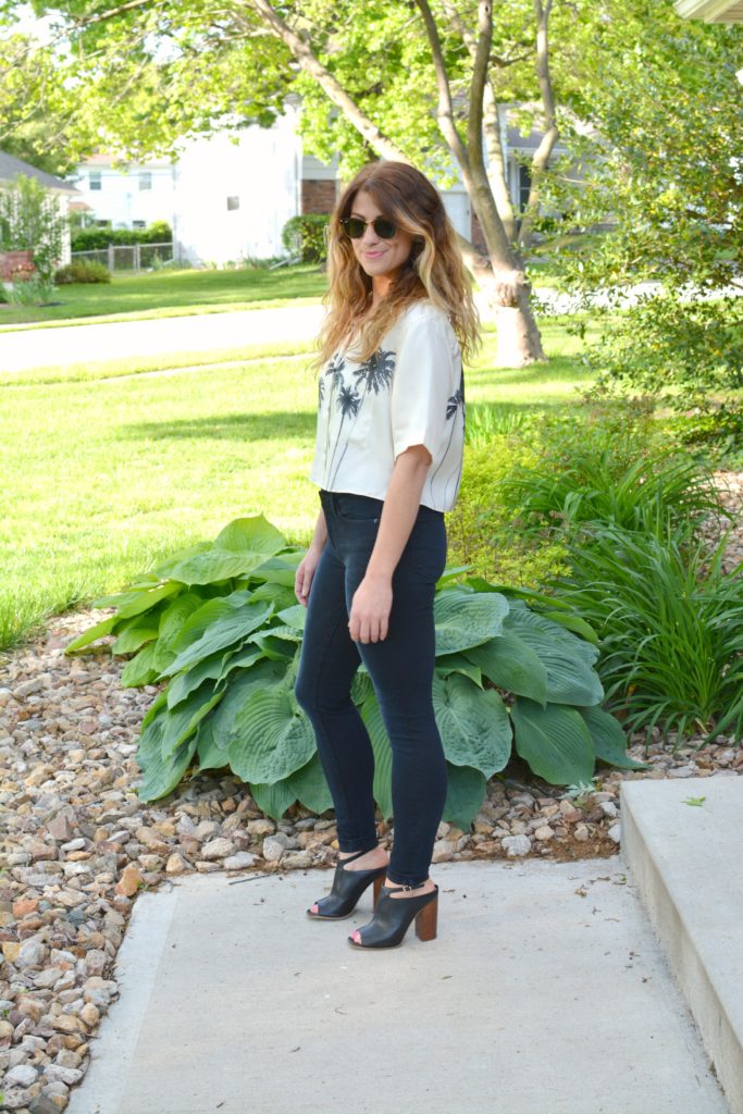 Ashley from LSR in a palm tree crop top, Frame jeans, and black mules