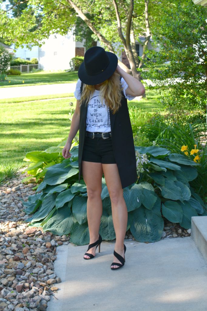 Ashley from LSR in a Sex & Ice Cream tee, long black vest, and black sandals
