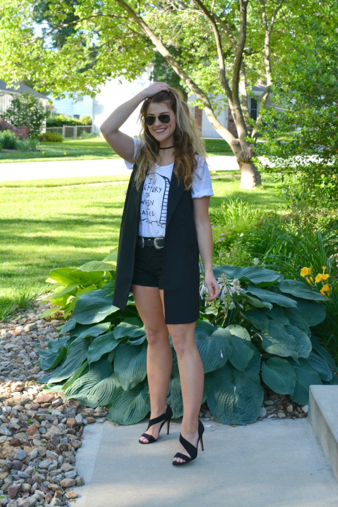 Ashley from LSR in a Sex & Ice Cream tee, long black vest, and black sandals