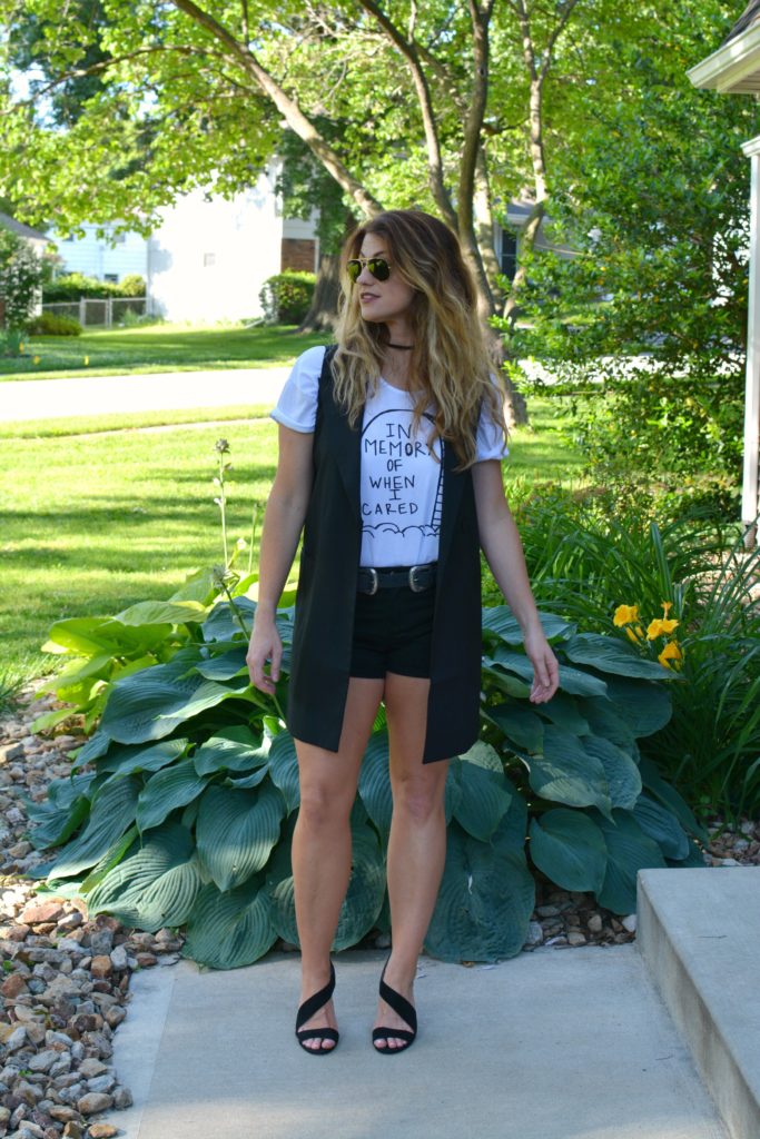 Ashley from LSR in a Sex & Ice Cream tee, long black vest, and black sandals