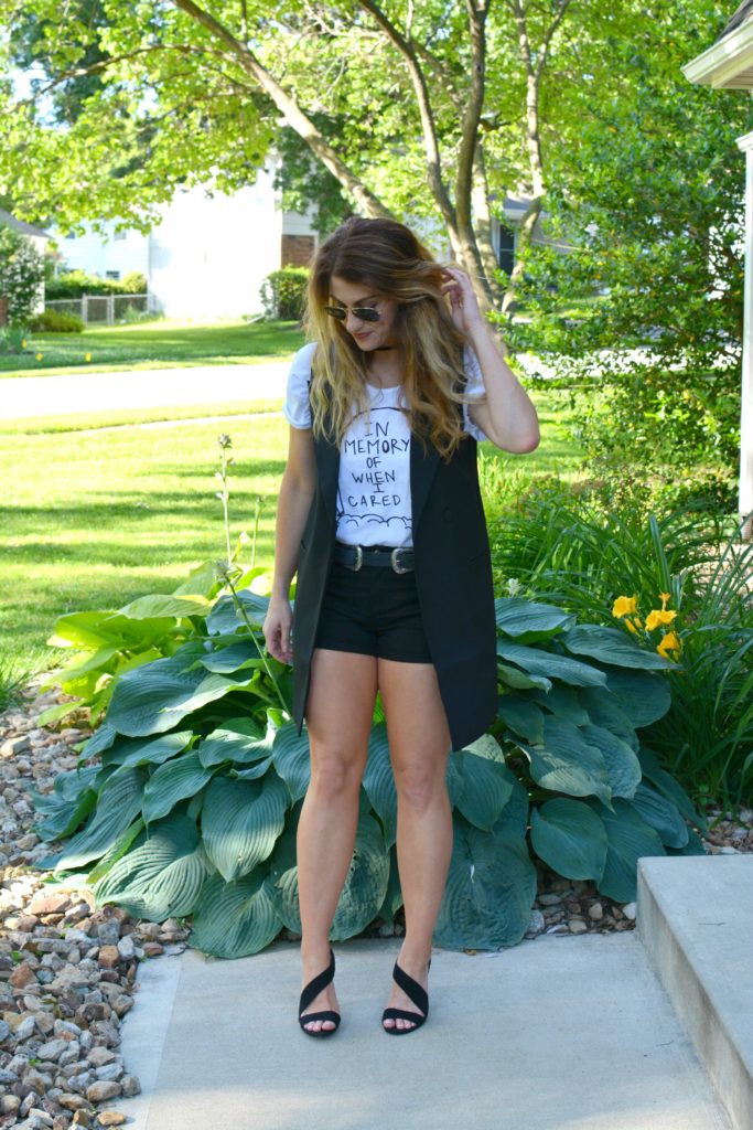 Ashley from LSR in a Sex & Ice Cream tee, long black vest, and black sandals