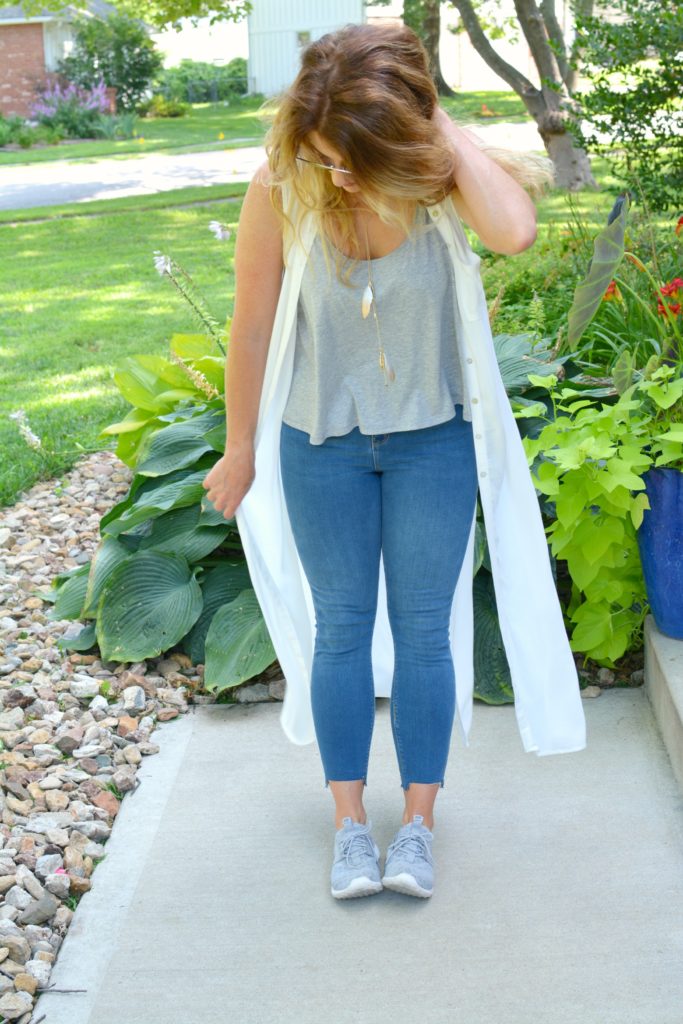 Ashley from LSR in a white duster, stepped hem jeans, and gray Nike's