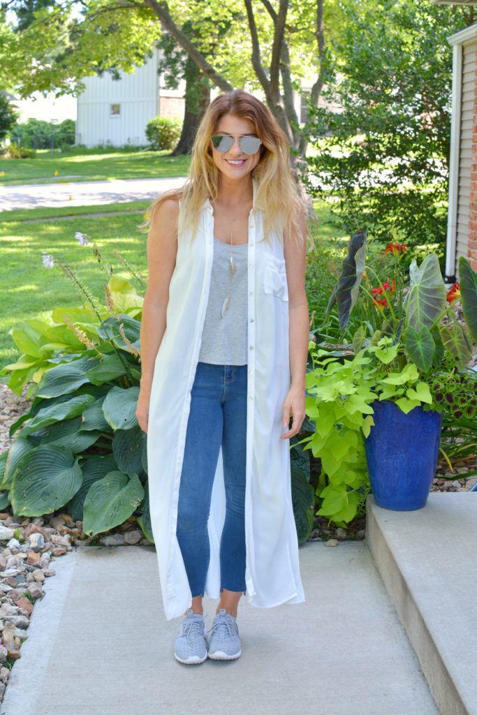 Ashley from LSR in a white duster, stepped hem jeans, and gray Nike's