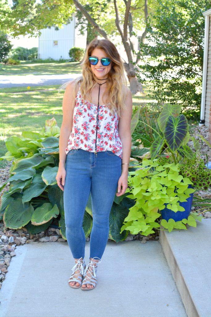 Ashley from LSR in a floral tank, stepped hem jeans, and white lace-up sandals