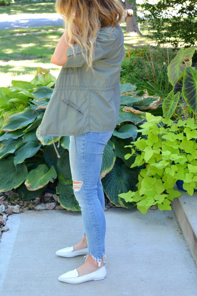 Ashley from LSR in an olive green utility jacket, destroyed denim, and white loafers