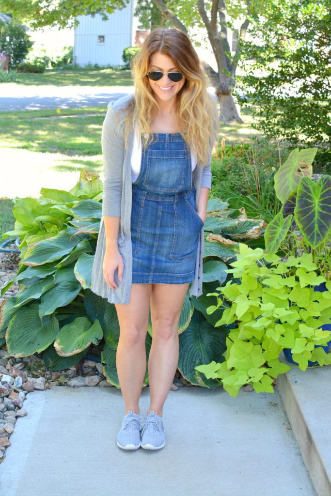 Ashley from LSR in an overall dress, gray cardigan, and gray Nike Juvenate sneakers