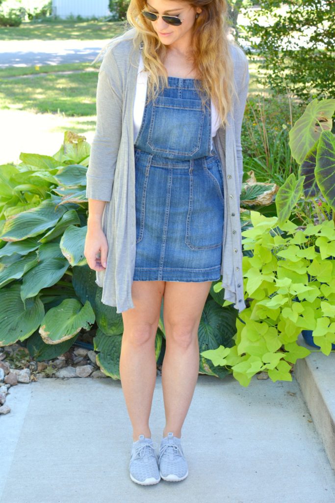 Ashley from LSR in an overall dress, gray cardigan, and gray Nike Juvenate sneakers