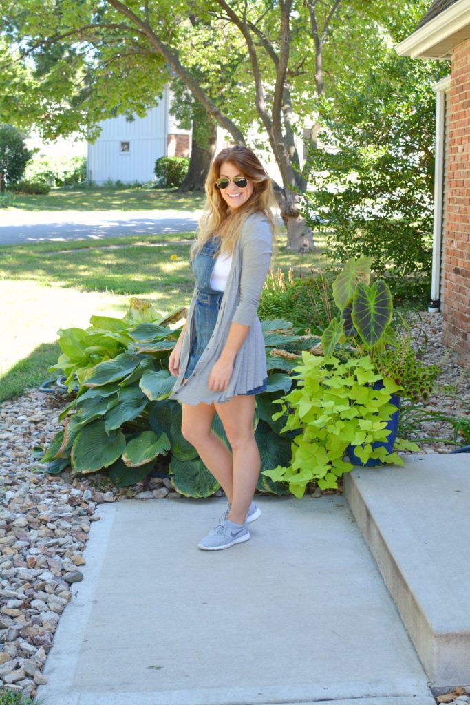 Ashley from LSR in an overall dress, gray cardigan, and gray Nike Juvenate sneakers