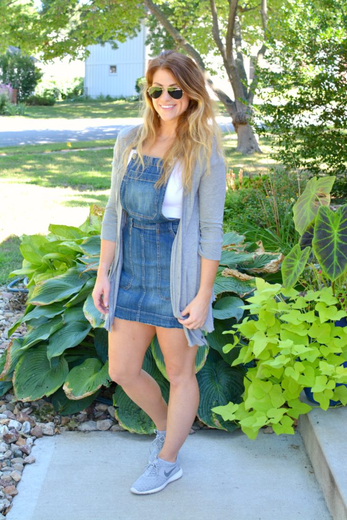 Ashley from LSR in an overall dress, gray cardigan, and gray Nike Juvenate sneakers