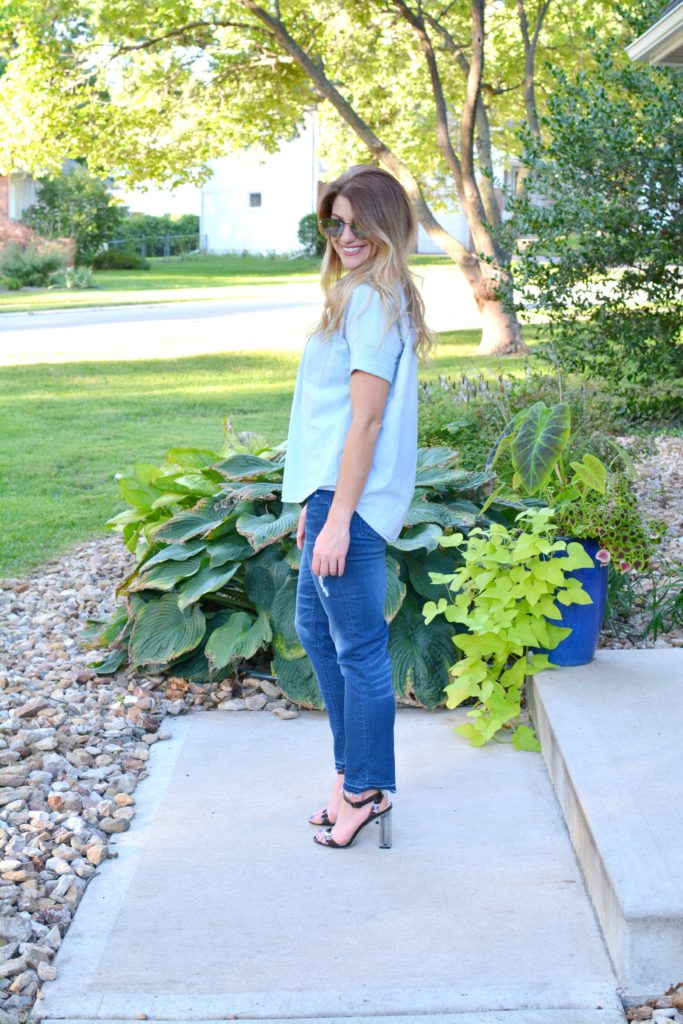 Ashley from LSR in a light chambray shirt, raw hem jeans, and lucite heels