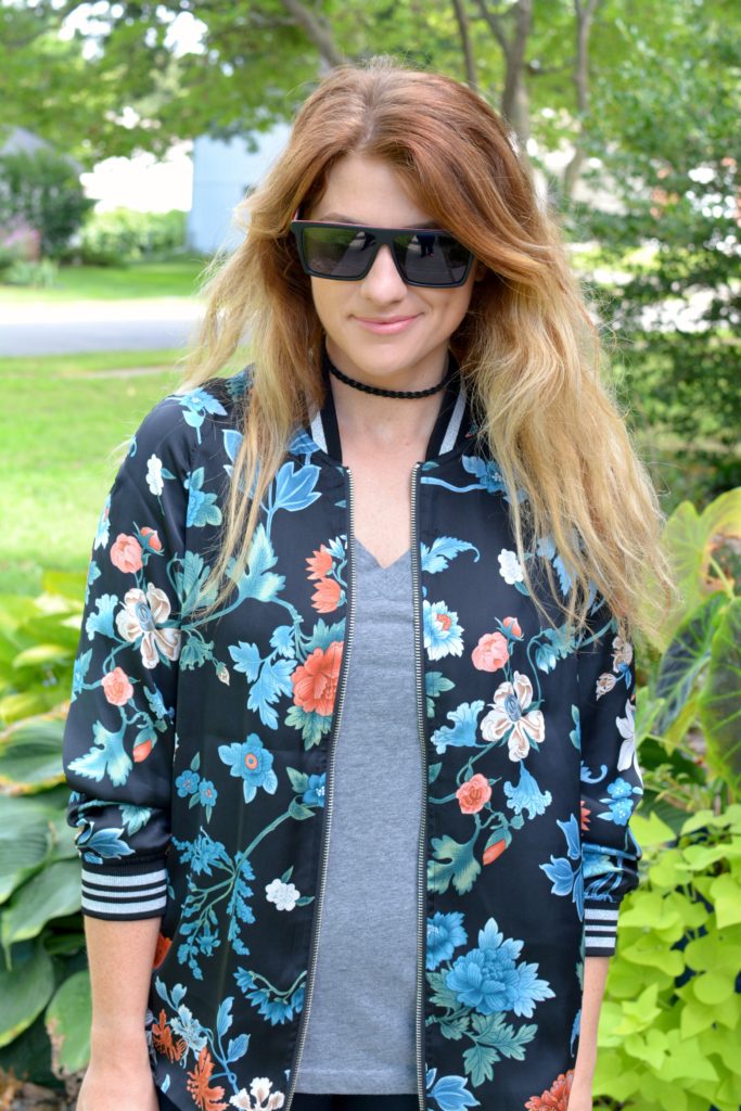 Ashley from LSR wearing a floral bomber jacket from H&M with a gray t-shirt and Proof sunglasses