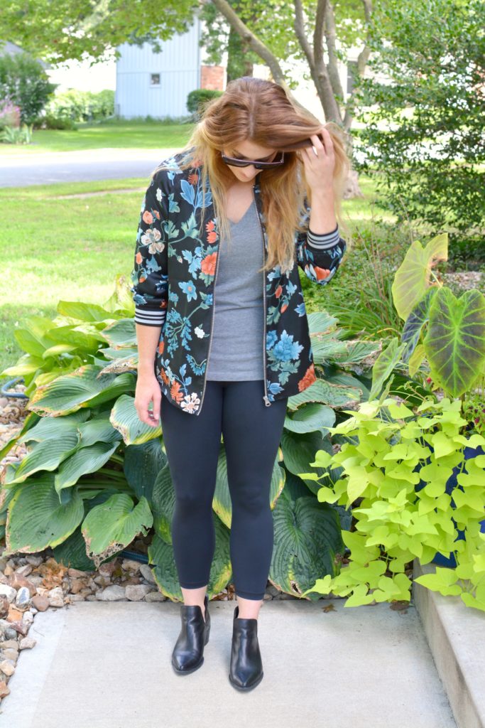 Ashley from LSR wearing a floral bomber jacket from H&M with black leggings and ankle boots