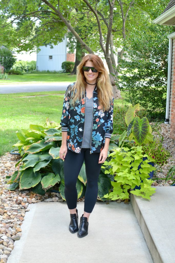 Ashley from LSR wearing a floral bomber jacket from H&M with black leggings and ankle boots