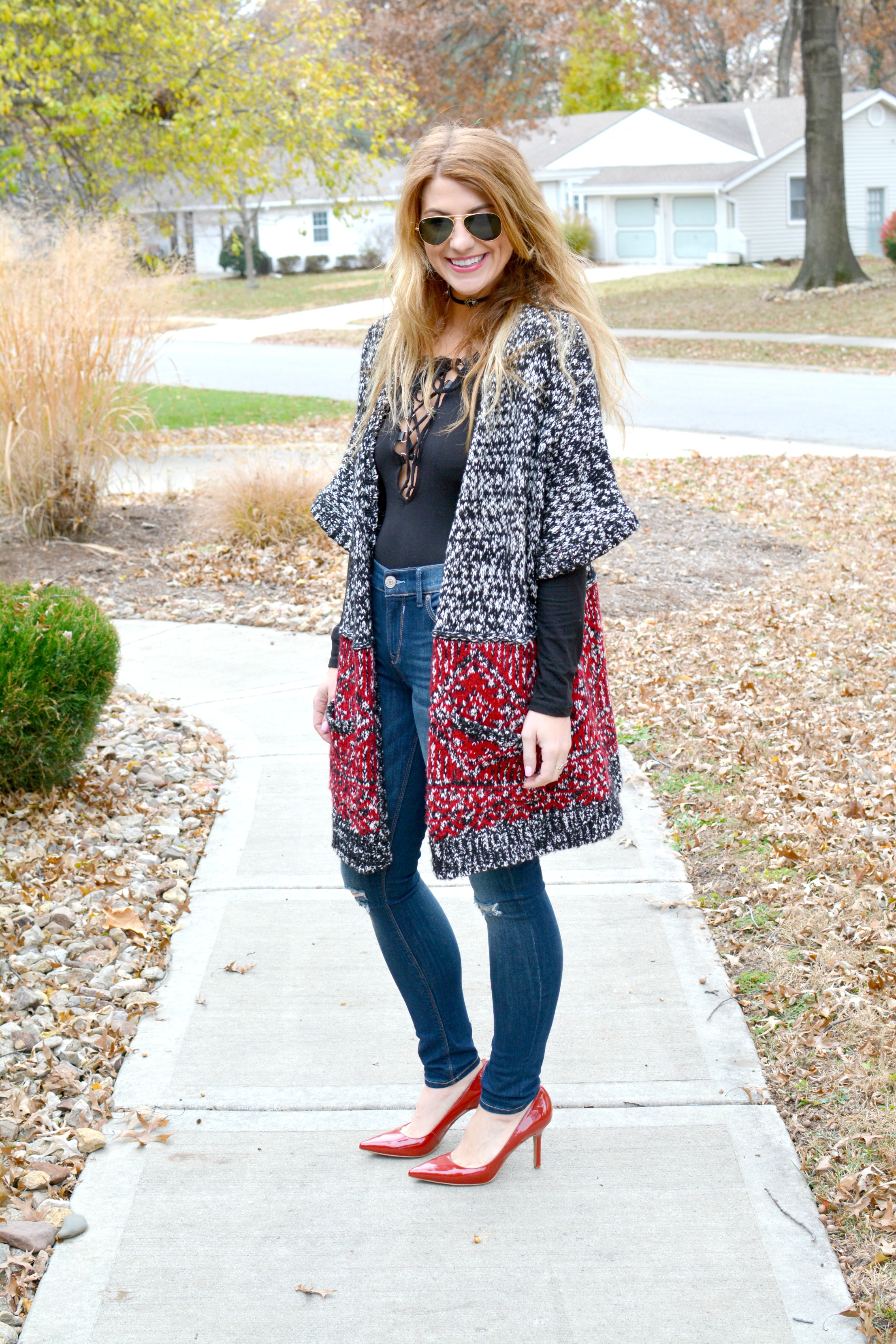 Ashley from LSR in a long cardigan, lace-up bodysuit, and red pumps