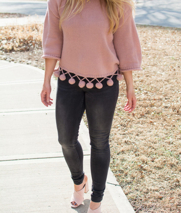 Ashley from LSR in a pink pom pom sweater with black denim and pale pink suede mule sandals